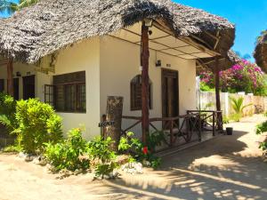 a small white house with a thatched roof at Jambiani White Sands Bungalows in Jambiani