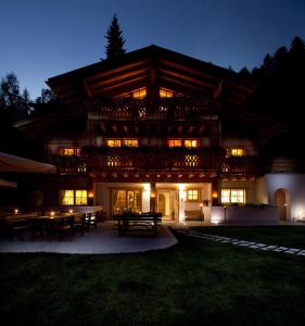 un grande edificio in legno con tavoli di fronte ad esso di notte di Fogajard Lovely Chalet a Madonna di Campiglio