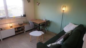 Rekerlanden 267 في فارمينهاوْسِن: غرفة معيشة مع أريكة خضراء وطاولة