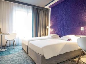 1 dormitorio con 2 camas y pared púrpura en Mercure La Roche Sur Yon, en La Roche-sur-Yon