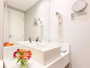 a bathroom with a sink, mirror, and bathtub at Mercure Sao Paulo Vila Olimpia in São Paulo