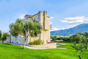 un grand bâtiment en pierre avec une pelouse verte dans l'établissement Villa Ostria, à Georgioúpoli