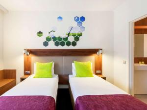 two beds in a small room with a blue wall at Ibis Styles Vilnius in Vilnius
