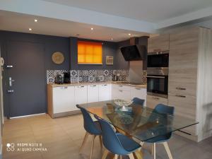a kitchen with a glass table and blue chairs at le cytharis in La Ciotat