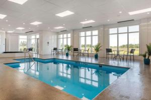 a pool in a room with chairs and tables at Quality Inn & Suites Mont-Joli in Mont-Joli