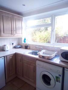 a kitchen with a washing machine and a sink at Large double room or single room with shared bathroom in Ash