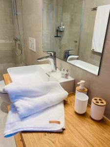 y baño con lavabo, toallas y espejo. en Britannia - Apartment Patagonia en Saas-Fee