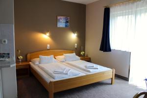 a bedroom with a bed with white sheets and pillows at Lídia Hotel in Harkány