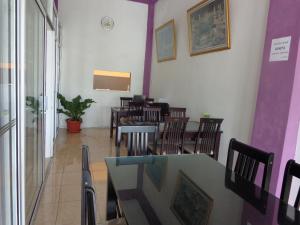 a dining room with tables and chairs and purple walls at Hotel Musafir Inn in Padang