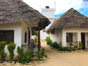 
a white house with a white roof and a white clock tower at Jambiani White Sands Bungalows in Jambiani
