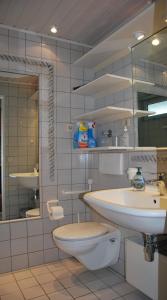 ein Badezimmer mit einem Waschbecken, einem WC und einem Spiegel in der Unterkunft Haus Nautic Whg. 810 in Cuxhaven