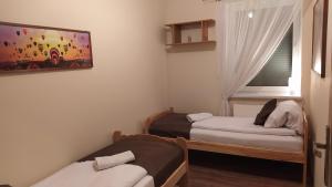 a small room with two beds and a window at Apartament na Kawiarach in Gniezno