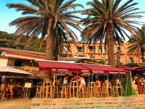 a group of people sitting at a restaurant with palm trees at La MAISON du PORT in Port-Cros