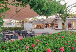 um pátio exterior com mesas, cadeiras e flores em Golden Club Cabanas em Cabanas de Tavira