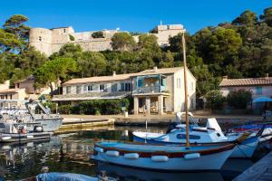 a boat docked in a harbor with a castle in the background at La MAISON du PORT in Port-Cros
