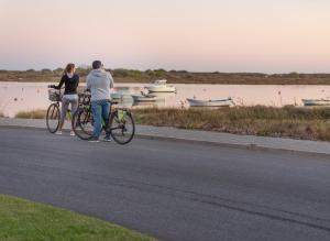 a man and a woman riding bikes down a road at Golden Club Cabanas in Cabanas de Tavira