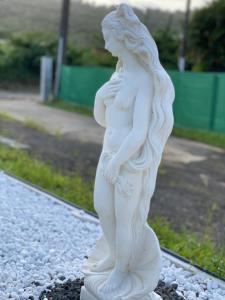 a white statue of a woman standing on a rock at Les Trésors de Laurëlia in Gourbeyre