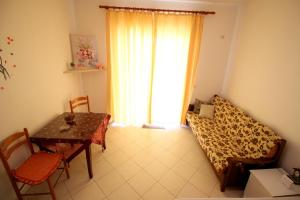 a living room with a table and a couch and a window at Mona`s apartments 1 in Sarandë
