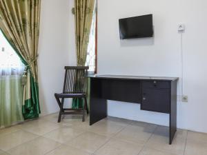 einen Schreibtisch mit einem TV an der Wand mit einem Stuhl in der Unterkunft OYO 3789 Bukit Somber Residence Syariah in Kampung Baru