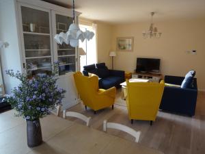 a living room with yellow chairs and a couch at Bootsman gelijkvloers appartement met tuin en autostaanplaats in Ostend