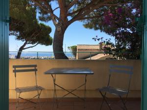 2 Stühle und ein Tisch auf einem Balkon mit Strandblick in der Unterkunft Jardins du Port Les Issambres - Meublé de Tourisme - Front de mer - Clim in La Garonnette-Plage