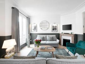 ein Wohnzimmer mit einem Sofa und einem Tisch in der Unterkunft LivinParis - Luxury 3 Bedrooms Opera II in Paris