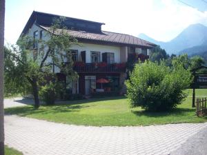 una grande casa su un campo verde con montagne di Ferienhaus Michor a Latschach ober dem Faakersee Altre 14 foto