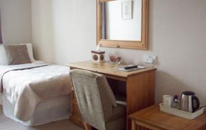 1 dormitorio con cama y escritorio con espejo en Lairg Highland Hotel, en Lairg