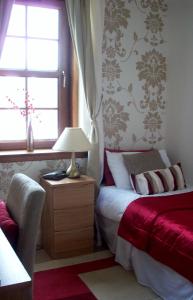 1 dormitorio con 1 cama con lámpara y ventana en Lairg Highland Hotel, en Lairg