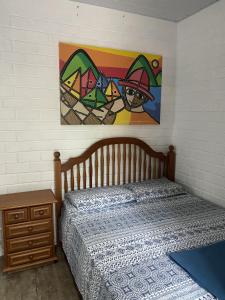 1 dormitorio con 1 cama y una pintura en la pared en Pousada Familia Quandt, en Guarda do Embaú