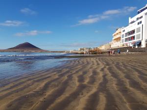 een strand met mensen die op het zand lopen bij Alquilaencanarias-Medano, Cabezo beach & pool in El Médano