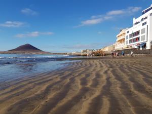 una playa con gente caminando por la arena en Alquilaencanarias-Medano, Cabezo beach & pool, en El Médano
