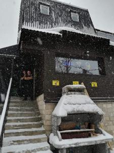 a snow covered building with stairs in front of it at Apartments Artic in Jahorina