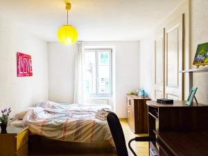 a bedroom with a bed and a desk and a window at Cozy Getaway in the Heart of the Swiss Riviera in Villeneuve
