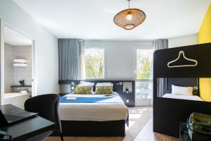 a bedroom with a bed and a desk and a laptop at The Originals Boutique Hotel Saint James, Montaigu-Vendée, Nantes Sud in Montaigu-Vendée