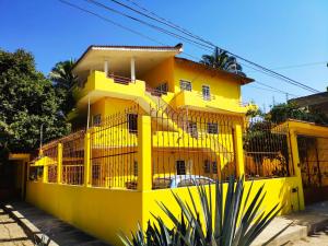 un bâtiment jaune avec une clôture devant lui dans l'établissement Habitación Hansa, à Puerto Vallarta