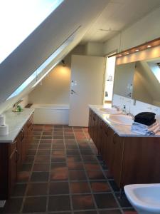 an attic bathroom with two sinks and a mirror at Dejligt værelse med eget bad og havudsigt in Assens