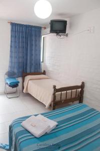 a bedroom with a bed and a tv on the wall at Hostel El Español in Colonia del Sacramento