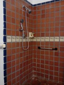 y baño con ducha y azulejos de color naranja. en Hotel Hacienda Bugambilias, en La Paz