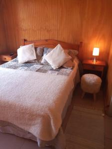 1 dormitorio con 1 cama con almohadas y silla en Hostal Playa Peñuelas, en Coquimbo