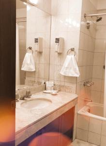 a bathroom with a sink and a mirror and a tub at Hotel Boulevard in Lima