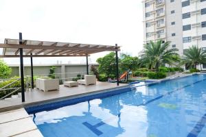 a pool with chairs and a pergola next to a building at Ezeniel's Place at Horizons 101 Condominium in Cebu City