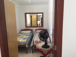 Habitación con ventilador, cama y espejo. en Aptos 5 pessoas a 50m do mar 025, en Florianópolis