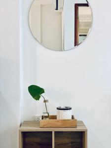 ein Spiegel an einer Wand neben einem Tisch mit einer Pflanze in der Unterkunft Loei Station in Loei