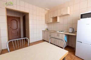ノヴォシビルスクにあるSiberia Apartmentsのキッチン(冷蔵庫、テーブル、カウンター付)