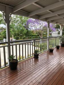 a porch with potted plants on a wooden deck at Tamborine Mountain Accommodation in Mount Tamborine