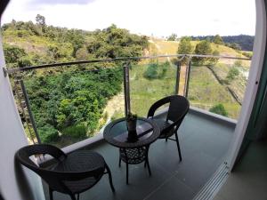 カジャンにあるNew Vacation Homestay @Forest Valleyの3脚の椅子とテーブル、景色を望むバルコニー