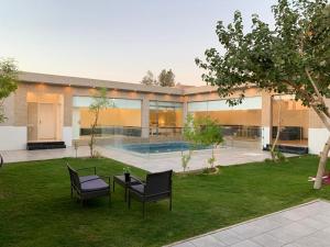 una casa con dos sillas y una mesa en un patio en شاليه الفورسيزونز, en Buraidah