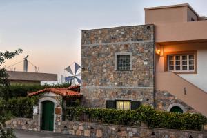 a house with a stone wall and windmills in the background at Anixiatiko Villa in Stalida