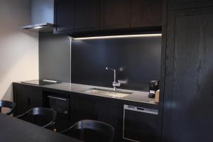 a kitchen with a sink and some black cabinets at Condominium ISHITEI Furano in Furano